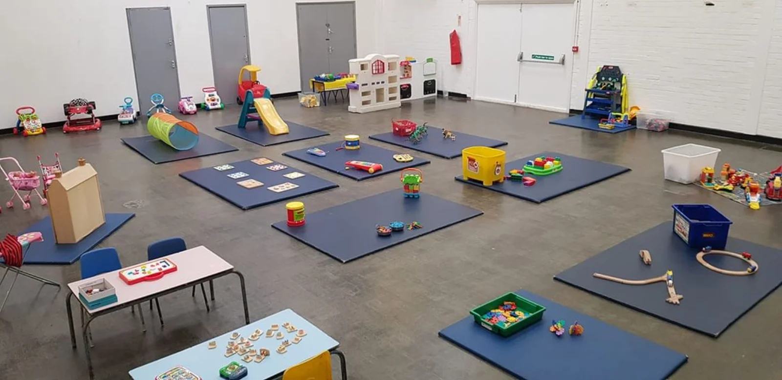 The Stay and Play room set up with soft play mats, toy kitchens, a slide and activity tables
